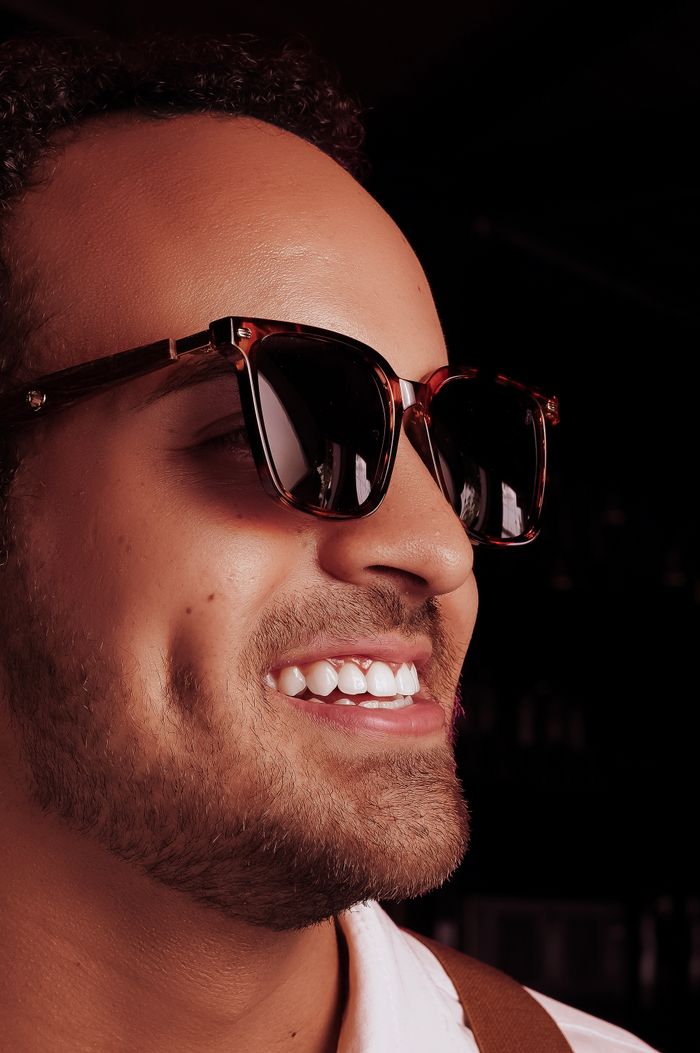 Close-up portrait of a smiling man wearing sunglasses, exuding confidence and style.