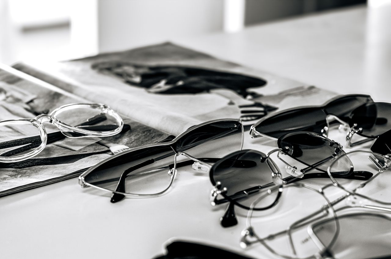 Stylish sunglasses arranged on a glossy magazine in a sleek black and white composition.