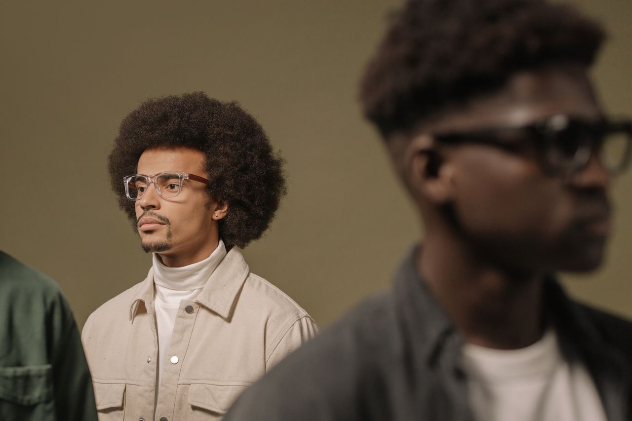 Fashionable men with afro hairstyles and eyeglasses, portraying modern style and confidence.